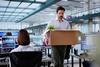 employee walks through office with cardboard box