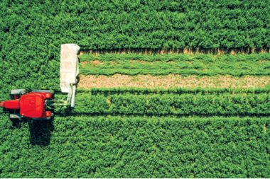 tractor mowing green field aerial view