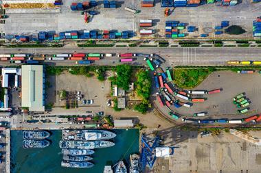 Birds eye view of lorries queuing at a transport hub near boats