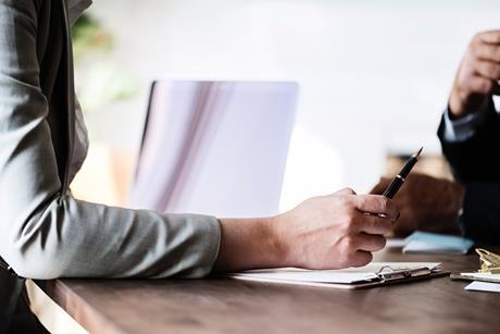 Photo of arm across a desk to signify a meeting, giving advice